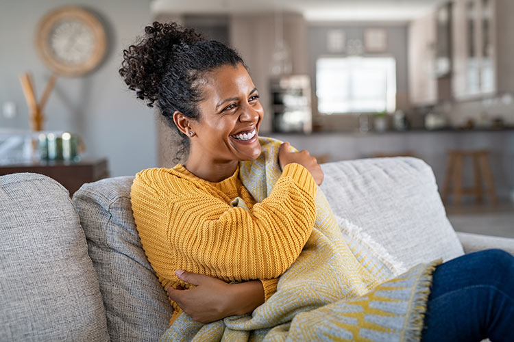 Joyful African American woman with blanket on therapy couch