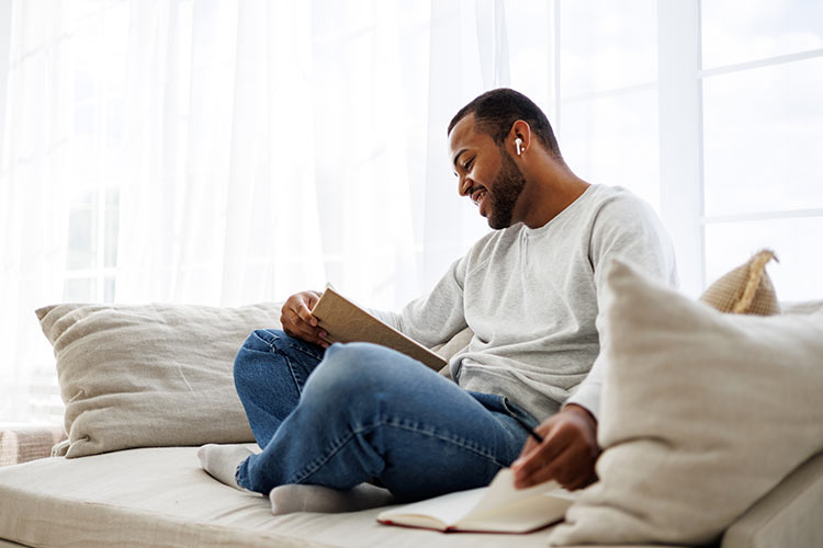 Younger African American man journaling on couch